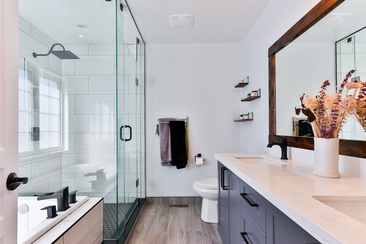 Badezimmer mit ebenerdiger Dusche hinter einer Glastrennwand in hellem, modernem Ambiente