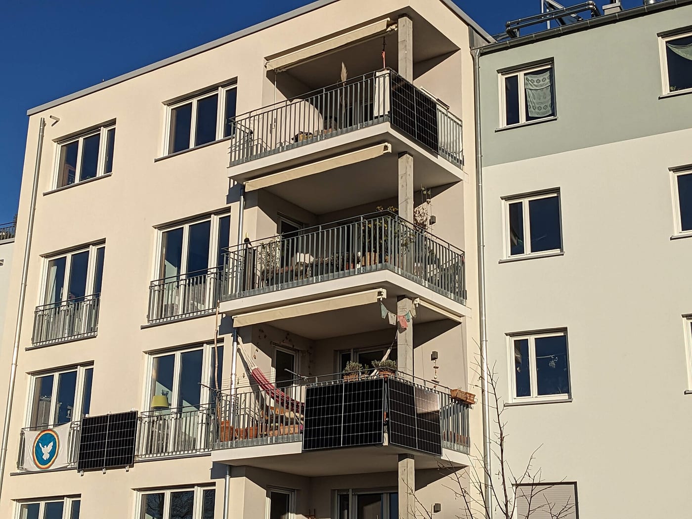 Mehrfamilienhaus mit Solarmodulen an mehreren Balkongeländern