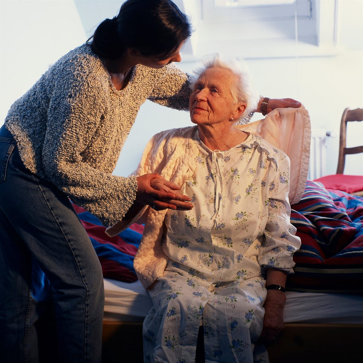 Betreuungskraft unterstützt eine Seniorin zu Hause am Bett – Seniorenbetreuung in Frankfurt-Ost mit ATERIMA CARE nach Krankenhausaufenthalt oder Reha.
