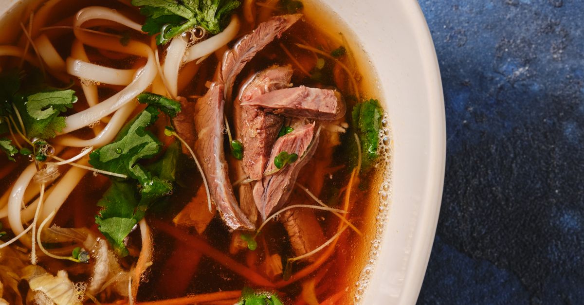 Dampfende Schale vietnamesische Pho mit Reisbandnudeln, Rindfleisch, frischen Kräutern und klarer Brühe