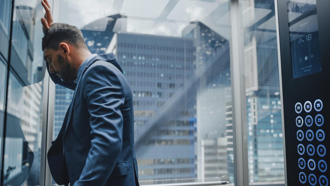 Berufstätiger in Frankfurt nutzt im gläsernen Aufzug eines modernen Business Centers sein Smartphone