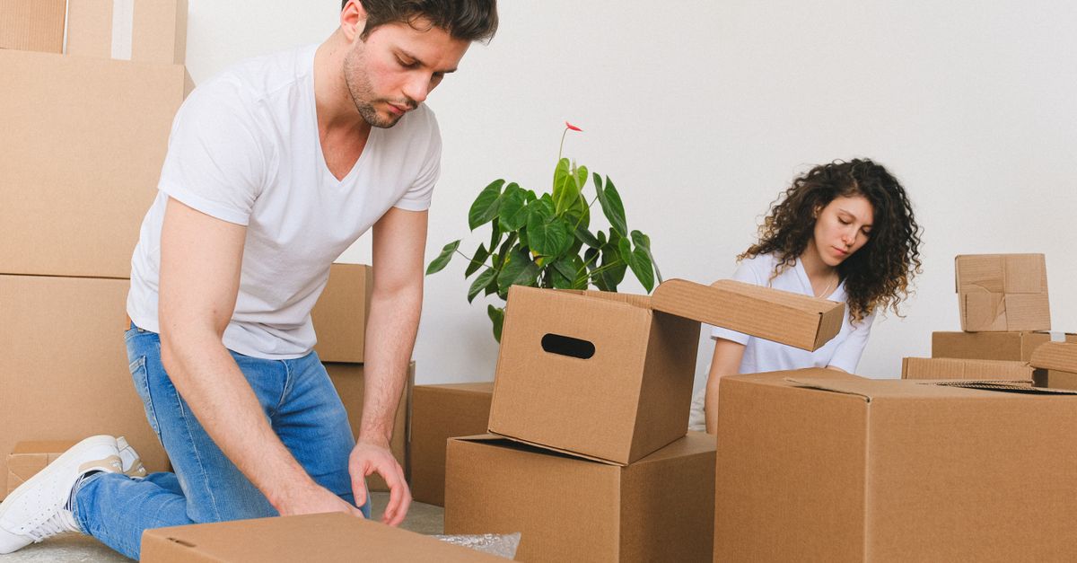 Junges Paar packt Umzugskartons in der neuen Wohnung aus und richtet gemeinsam ein gemütliches Zuhause ein